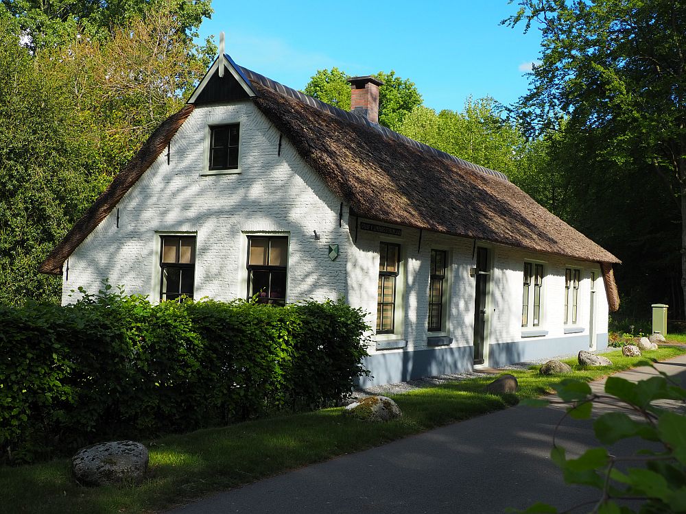 A simple white-painted house with a thatched roof.