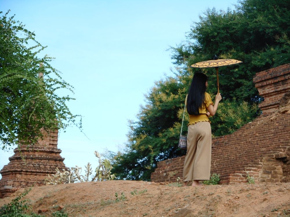 A woman holding a parasol looks at one of the stupas at Bagan, Myanmar.
