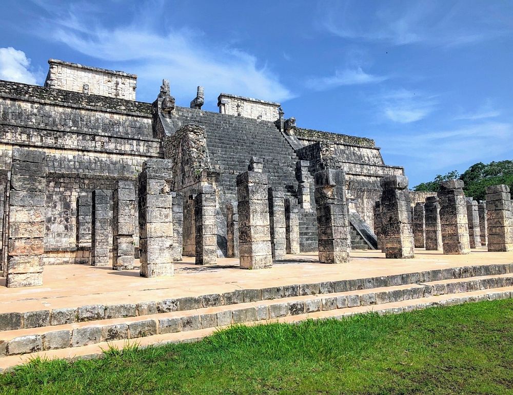 A flat platform (2 steps up from the ground) with rows of square columns. Behind them, a long stairway goes up to the top of a large building behind them.