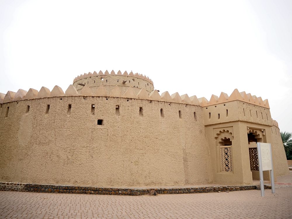 The tower isn't really a tower: it is a round building with a small entrance porch sticking out. A round tower stands inside the walls, but only a small bit of that tower can be seen from this vantage points, so the inner tower can't be much taller than the outer walls. The walls are topped with pointed crenellations and the wall has very small arrow slits just under the crenellations.