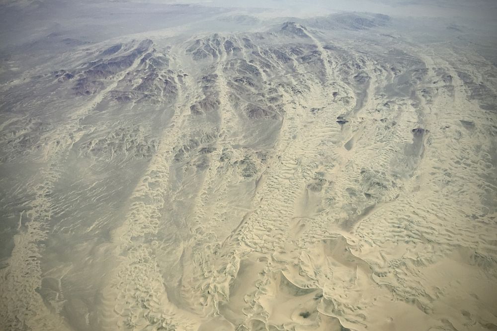 Aerial view shows nothing but sand, dunes and mountains.