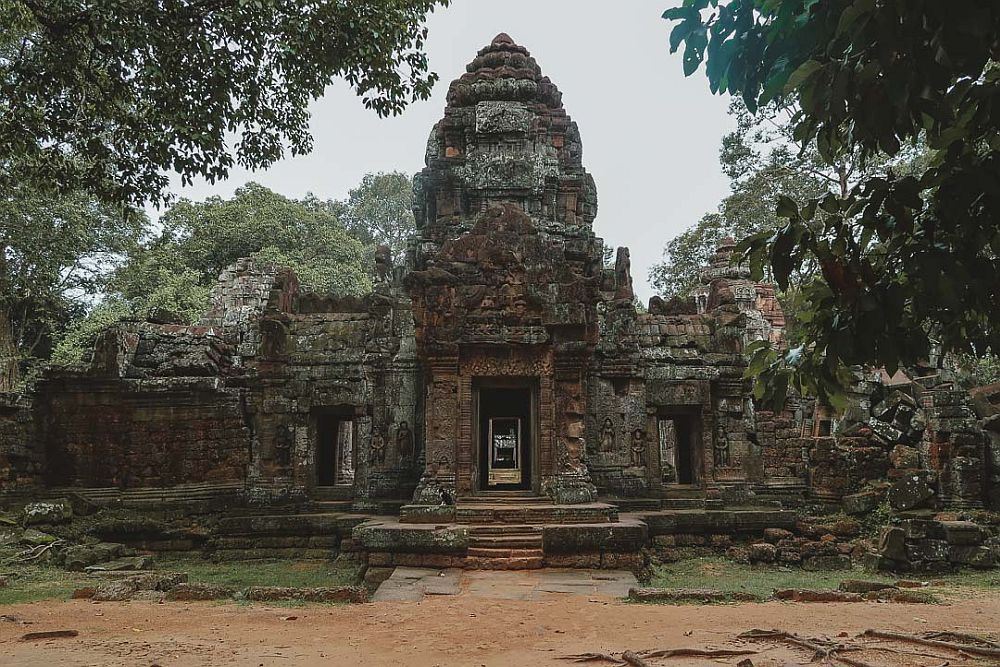 A stone building with a central doorway through which you can see through to the other side. A similar doorway on either side. Above the central one is a curved cone-shaped tower of stone with carved motifs.