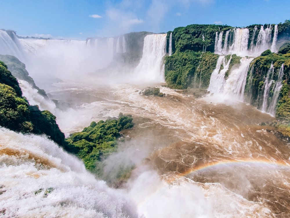 Iguacu falls coming down on both sides of a gorge, making the water in the gorge roil.