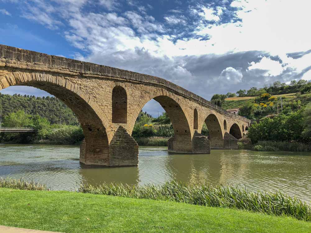 A stone bridge crosses a river in a series of neat arches.