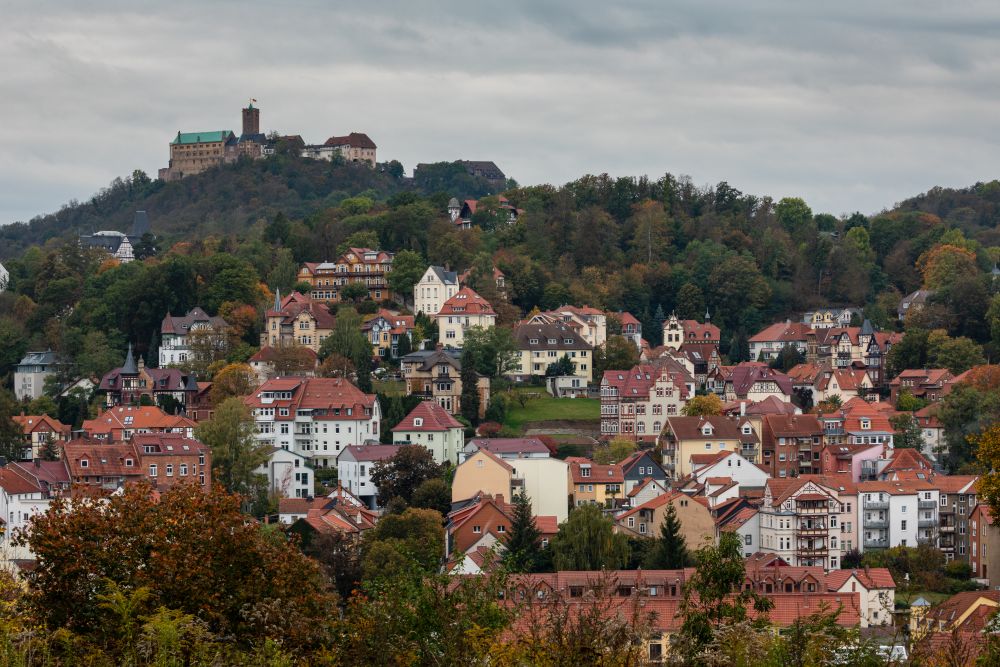 A cluster of houses below a hill. on top of the hill, Wartburg Castle with its tower.