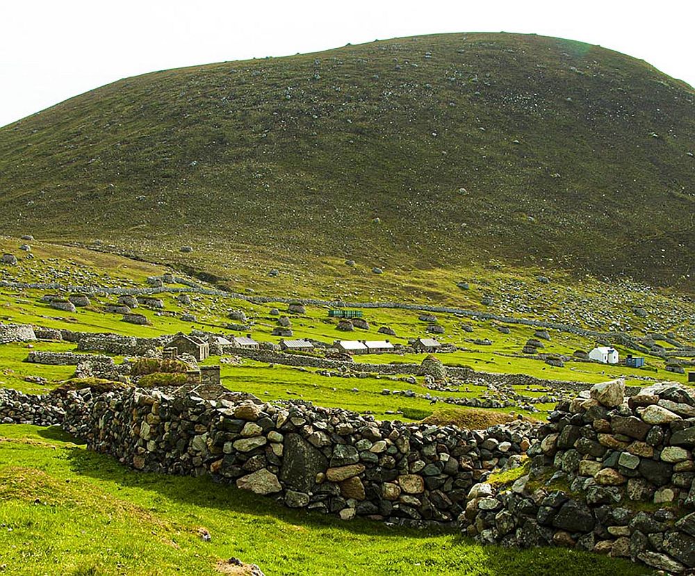 View of the remains of the village of St Kilda, with a hill rising behind it.
