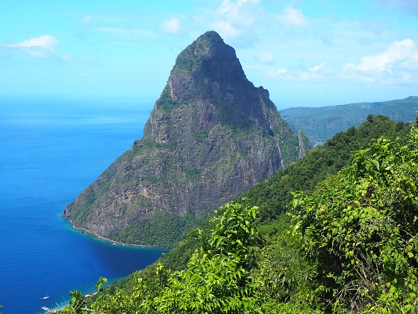 Petit Piton is in the shape of a steep cone coming straight out of the water (it's attached to land on one side, but that side is obscured by the nearby forest in this photo.) In parts it's covered with green growth. In other parts it's bare rock.