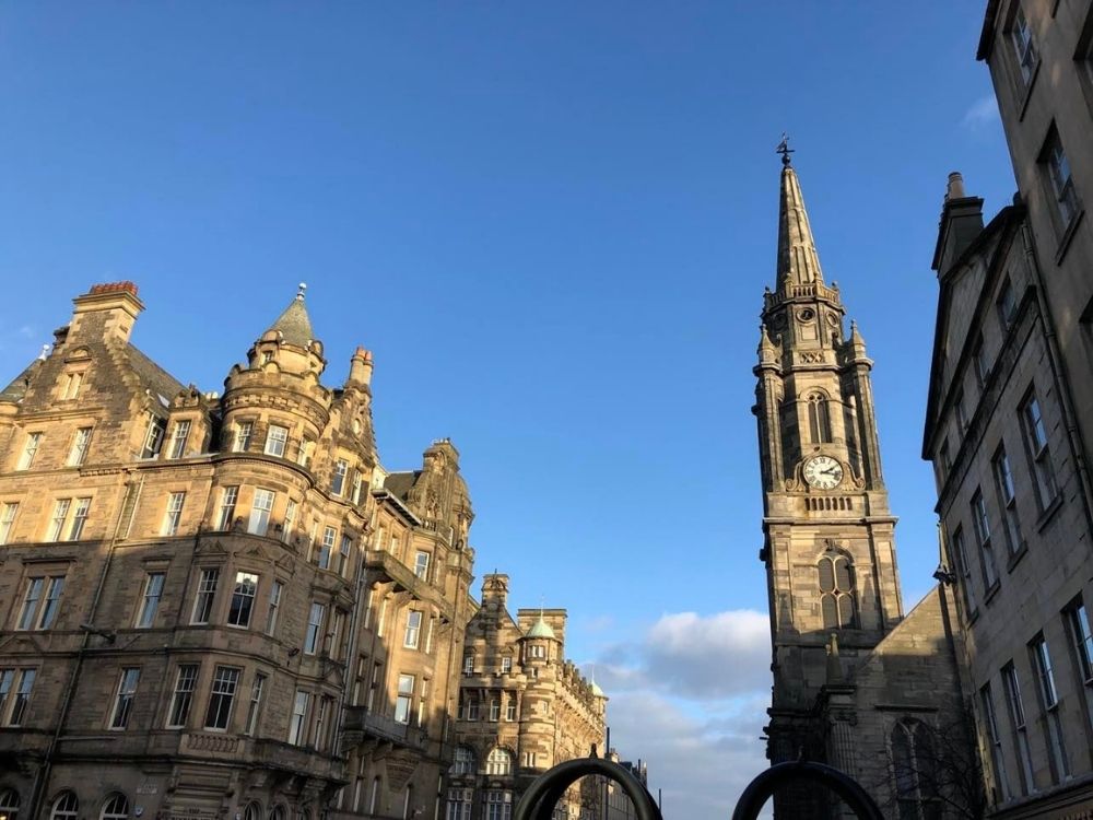 Looking up at some of Edinburgh's buildings: stone blocks, rounded elements on the corners; also a stone church steeple.