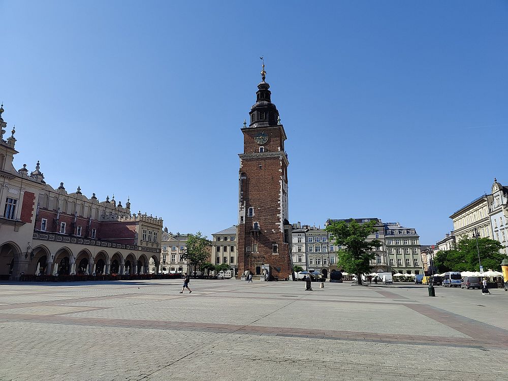 A huge empty market square in Krakow, Poland. At the far end is a tall square tower.