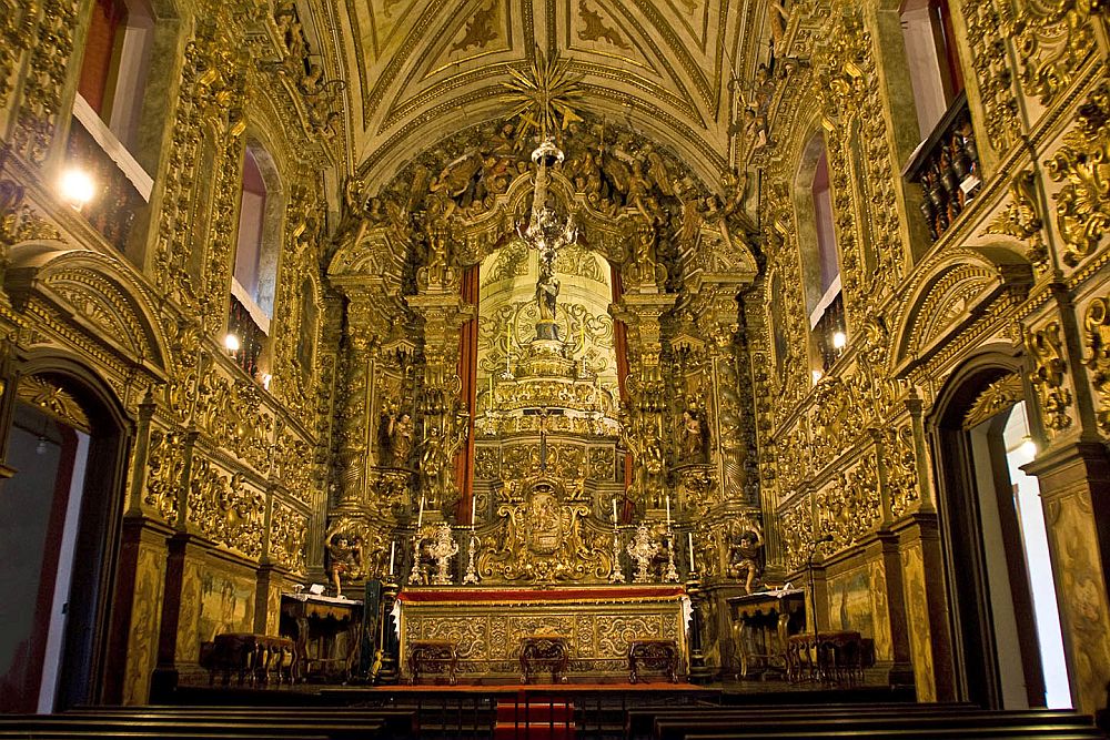 Facing the altar, with some of the side walls and arched ceiling visible. Every inch is ornately decorated with religious and natural imagery, as well as architectural features like arches and such. Literally all of it is covered in gold.