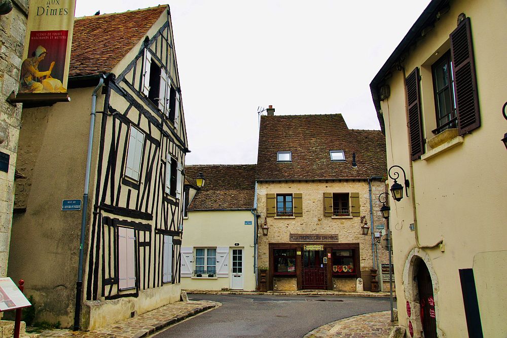 A short length of street in Provins lined with medieval-period houses. The one on the left is half-timbered.