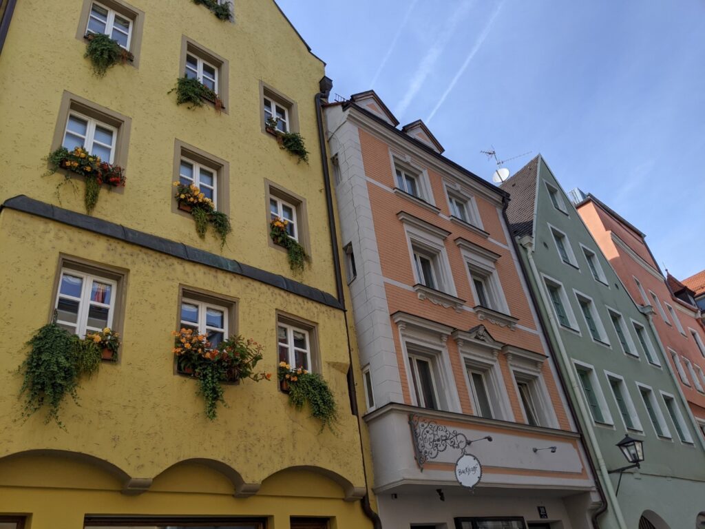 A row of buildings, each about 4-5 stories tall and each painted a different pastel color, in Regensburg, Germany. 