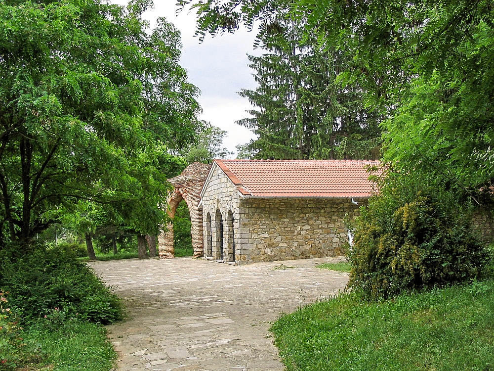 The outside of the Thracian tomb is a simple, single-story stone building with a red roof.