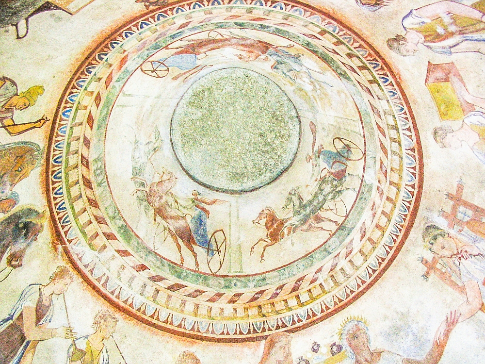 This fresco from the Thracian tomb is the center of the ceiling so it is circular. Around a central green circle race three horse-drawn chariots, each with two horses and one person standing in the chariot holding the reins.