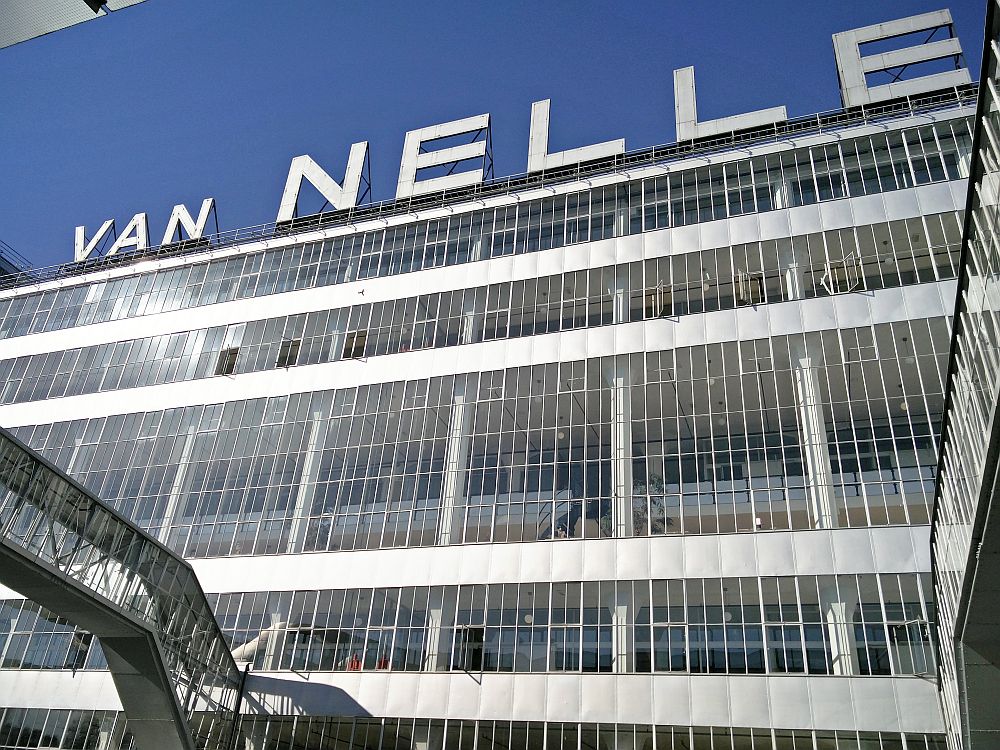 Looking up at the front of the Van Nellefabriek: lots of glass, with white horizontal panels at the floor of each story. Big letters on the roof that read "Van Nelle".