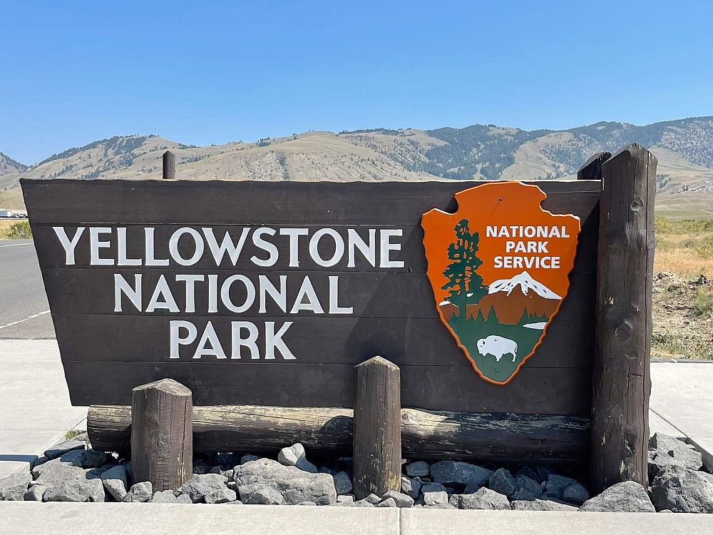 A wooden sign with the words "Yellowstone National Park" and next to that, the National Park Service crest.
