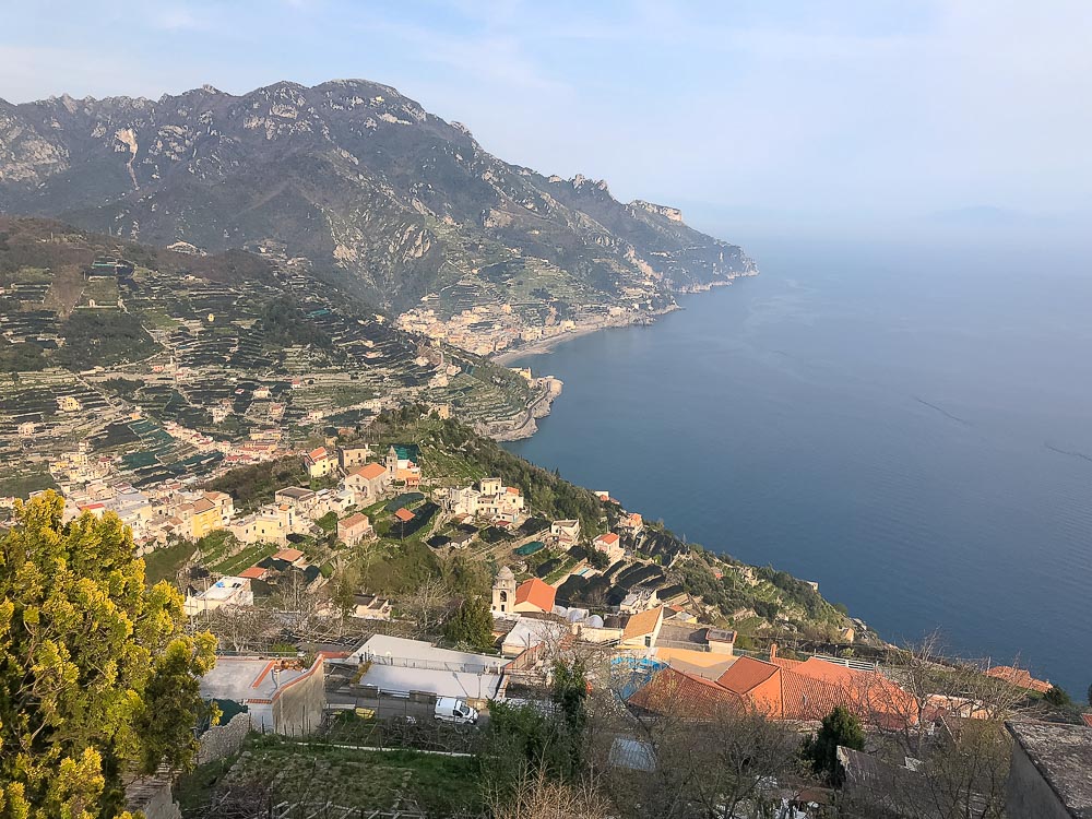 A view from the land over a section of the Amalfi Coast: clusters of houses on steep hills that drop into the sea.