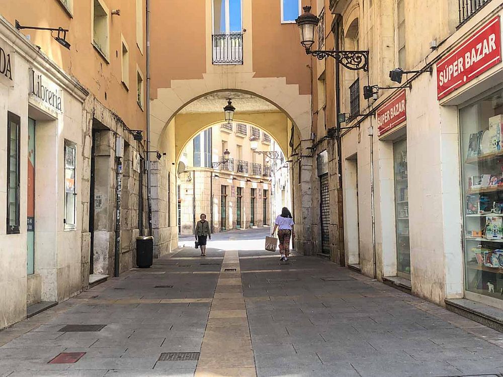 Looking down a narrow street, hemmed in on both sides by buildings. Straight ahead, an arch of a building over the street.