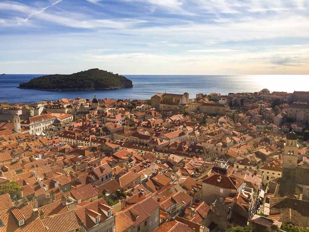 View over the old town of Dubrovnik: lots of red roofs and the blue sea beyond that.