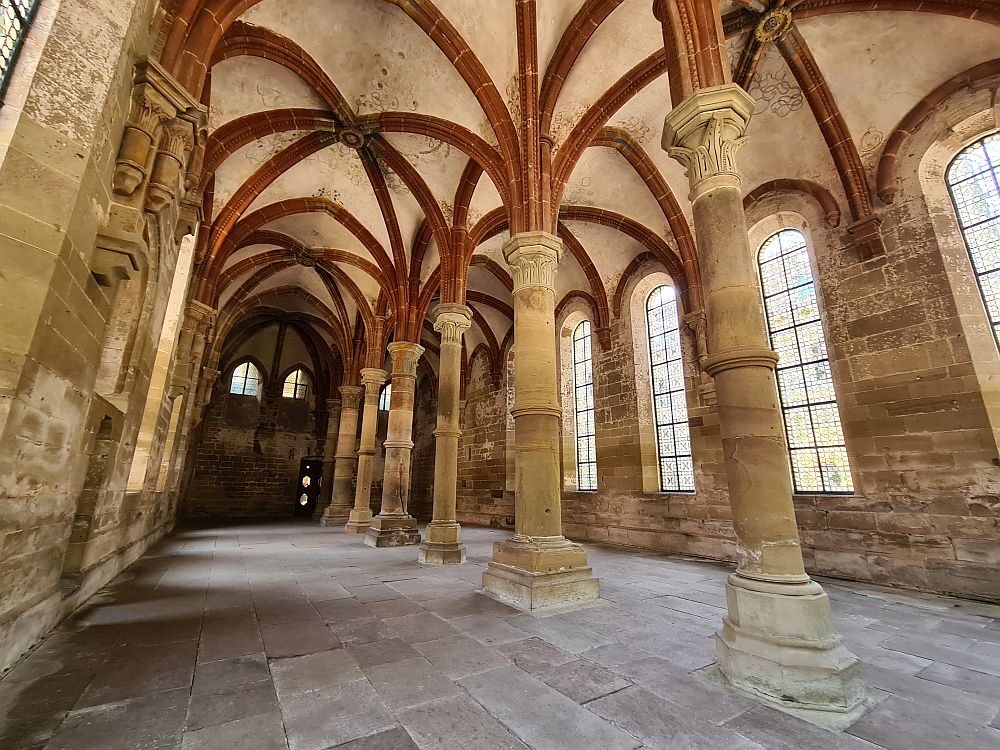 The hall is large, with a row of pillars down the center and tall arched windows on either side. the pillars support a ceiling with gothic arches.