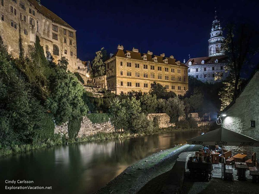 Night view of Český Krumlov shows imposing castle buildings rising above the river.