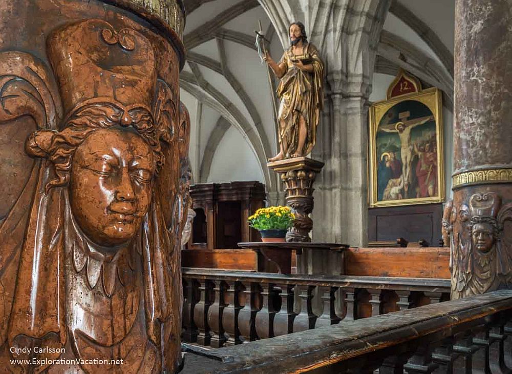 Interior view of a church in Český Krumlov: ornate artwork and gothic arches.