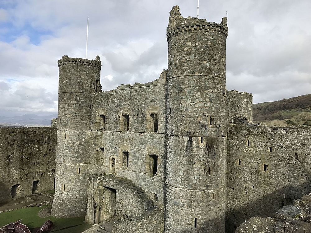 Harlech castle, in this view, has two round corner towers still more or less intact, and the wall between them too, with a doorway and two rows of windows above that.