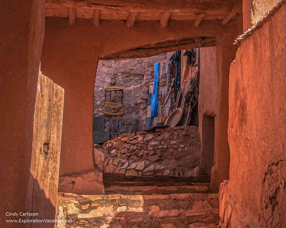 A view in an alley in the Ksar of Ait-Ben-Haddou: earthen walls, stone floor, and a section of a building that reaches over the alley shows wooden beams support it.