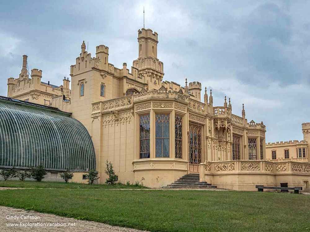 A different view of Lednice Castle: large ground floor windows with gothic arches at the tops, crenelations along the roofline for decoration, and several crenelated towers. 