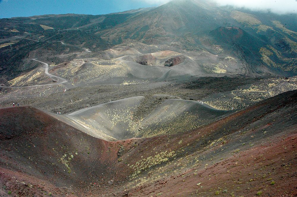 A view on the volcano over several different craters, another peak beyond them. 