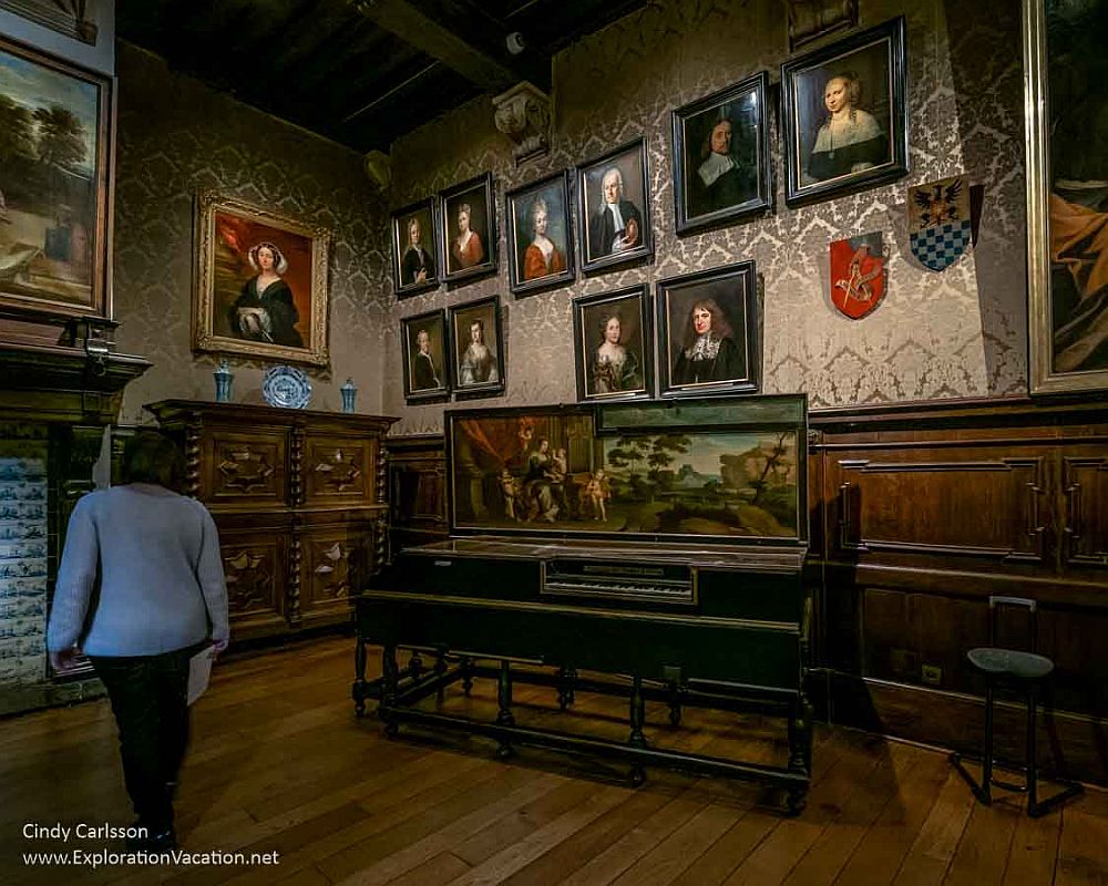 A room in the living space at the Plantin-Moretus Museum: the wall is covered with portraits: 11 are visible in the photo, plus a landscape and a group portrait on a table. 