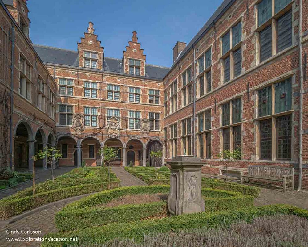 An exterior view of the Plantin-Moretus  Museum's courtyard: red brick, 2-3 stories high, with 2 gables visible, and a portico along the ground floor.