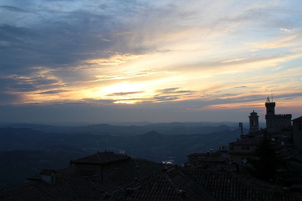 A view of the sunset, with the two towers of the castle at San Marino in silhouette at the right of the picture.