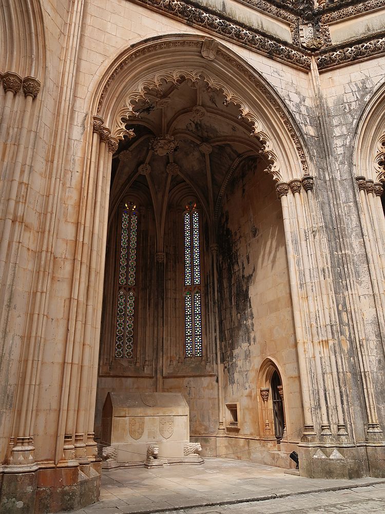 A very tall chapel in the cathedral, with a very high archway, edged with delicate stonework. Inside it are some narrow vertical stained glass windows and, on the floor, what looks like a simply-carved tomb.