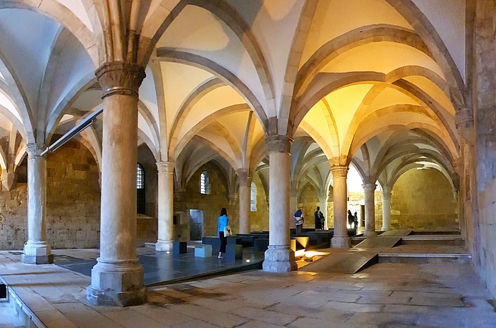 A large room with two rows of pillars and elegant Gothic vaulting between them at the Monastery of Alcobaça. 