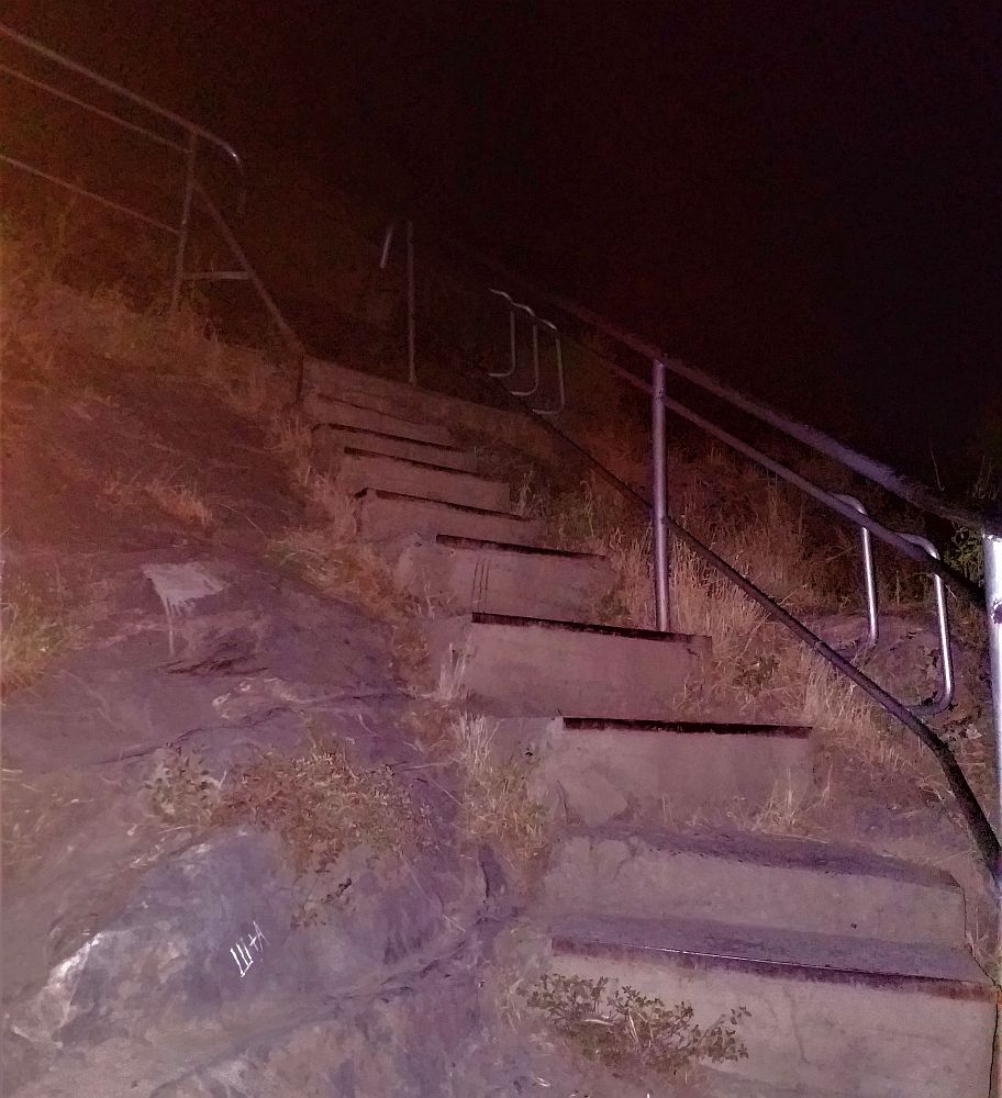 Concrete stairs with a metal railing leading up Sulaiman-Too Sacred Mountain.