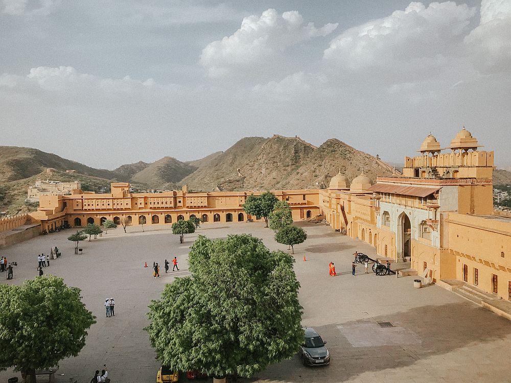 A view of a large plaza with walls of the fort on all visible sides, low on the far side (2-3 stories) and even lower on the left, but with a large ornate gateway on the right.