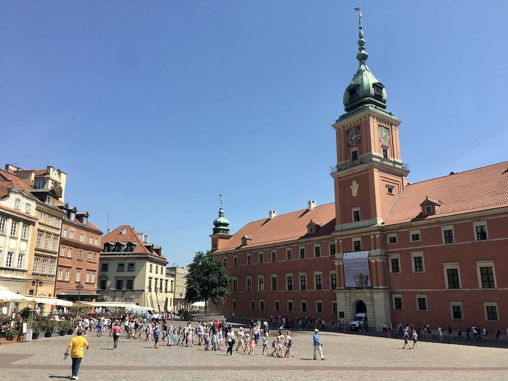 Market square in Warsaw: a row of buildings on the left, a large town hall building on the right: red brick, with a tower above its central entryway.