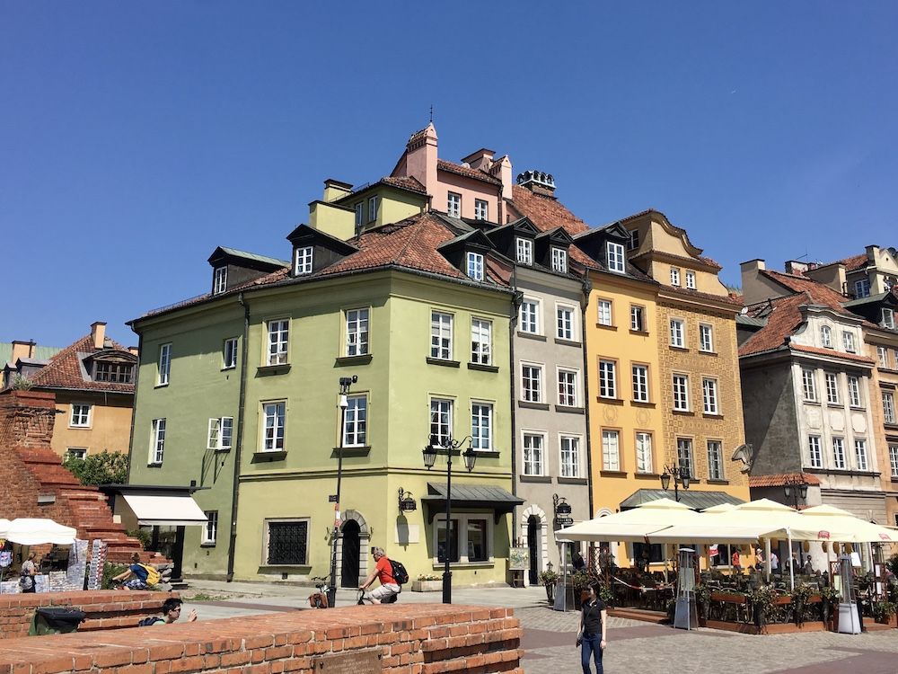 A row of buildings, 4-6 stories, painted in a range of pastel colors. In the Historic Centre of Warsaw, Poland.