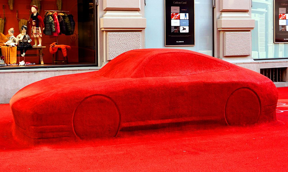 A sports car that is entirely covered in a bright red surface.
