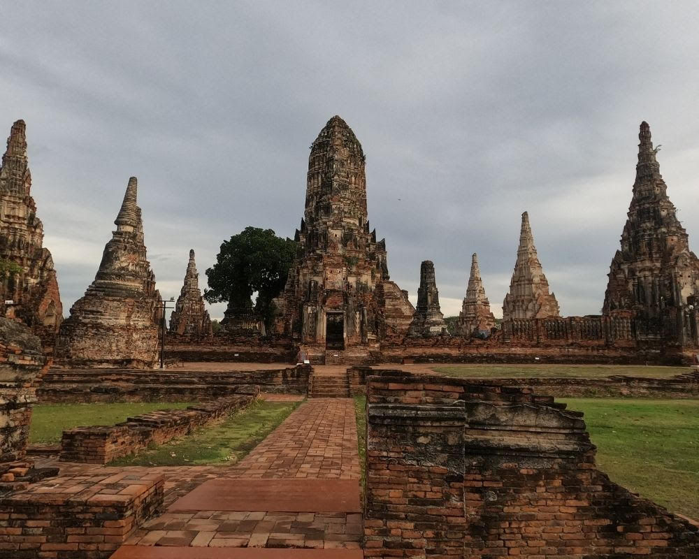 A group of stone and brick  temples, each with a tall pointed roof, at Ayutthaya.