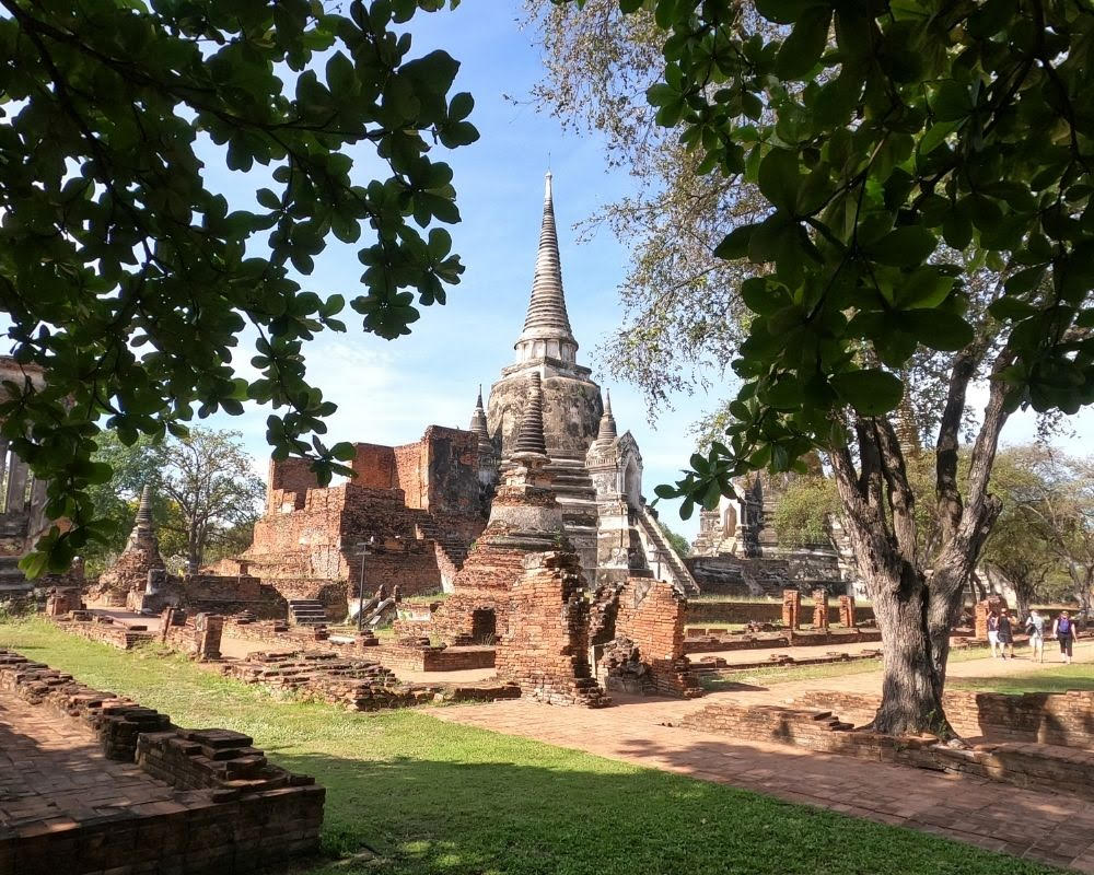 A view of a temple at Ayutthaya: a tall pointed stone stupa set on a platform of brick, with secondary stupas around it.