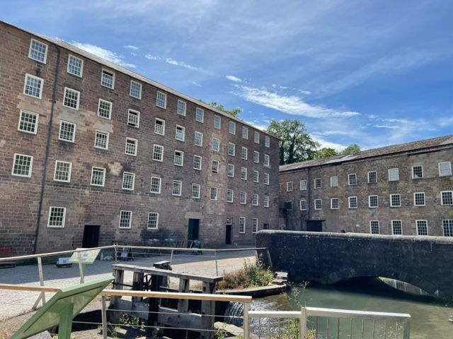 A five story building on the left, a three-story building at right angles to it. Both made of plain stone-cut blocks, both with rows of very simple square windows.