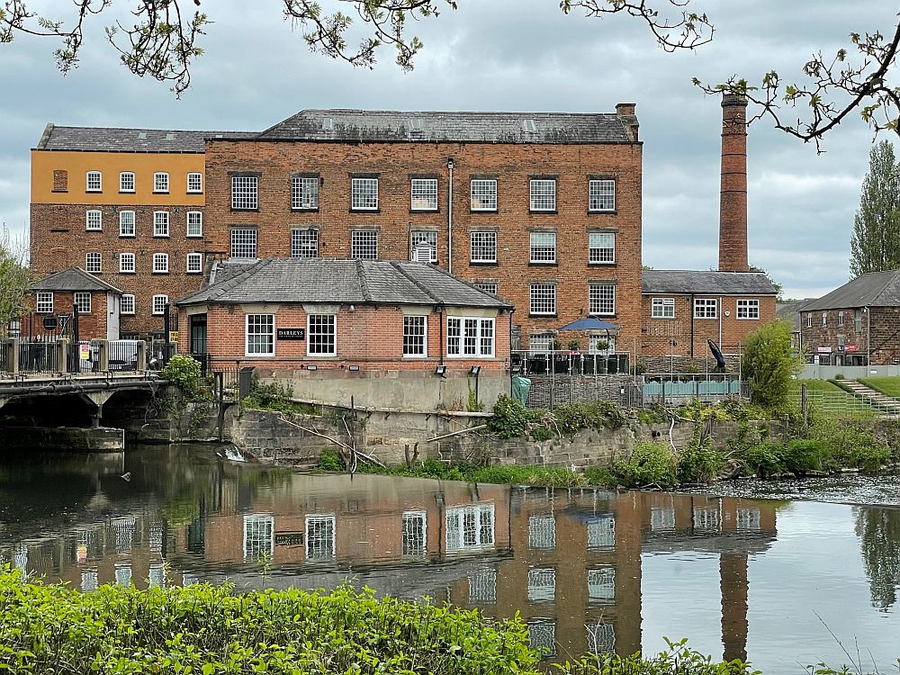 A red-brick factory building with a tall chimney next to it.