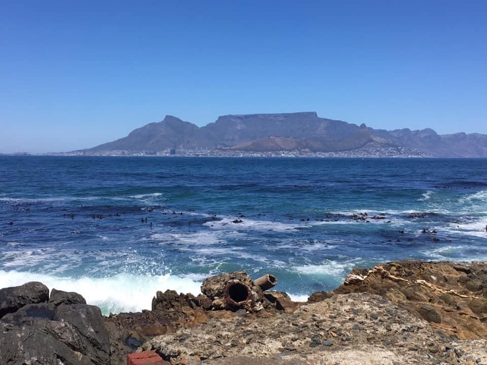 A view toward Capetown over blue ocean. Capetown and Table Mountain in the distance.