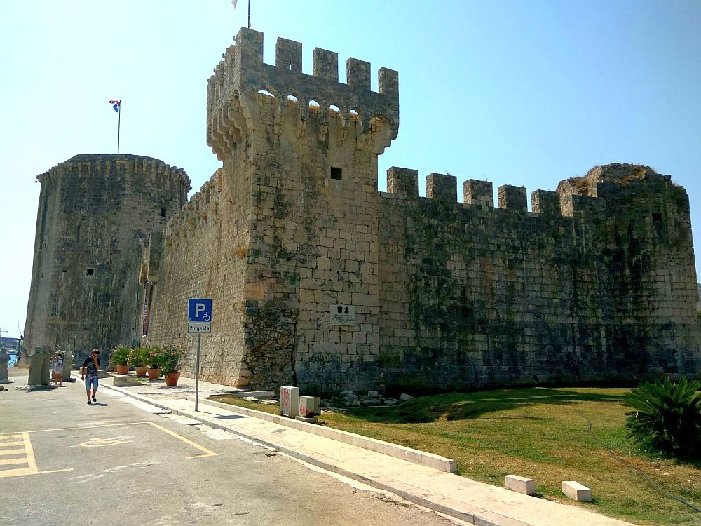 A medieval castle, with stone walls, towers at the corners and crenellations around the top, in Trogir, Croatia.