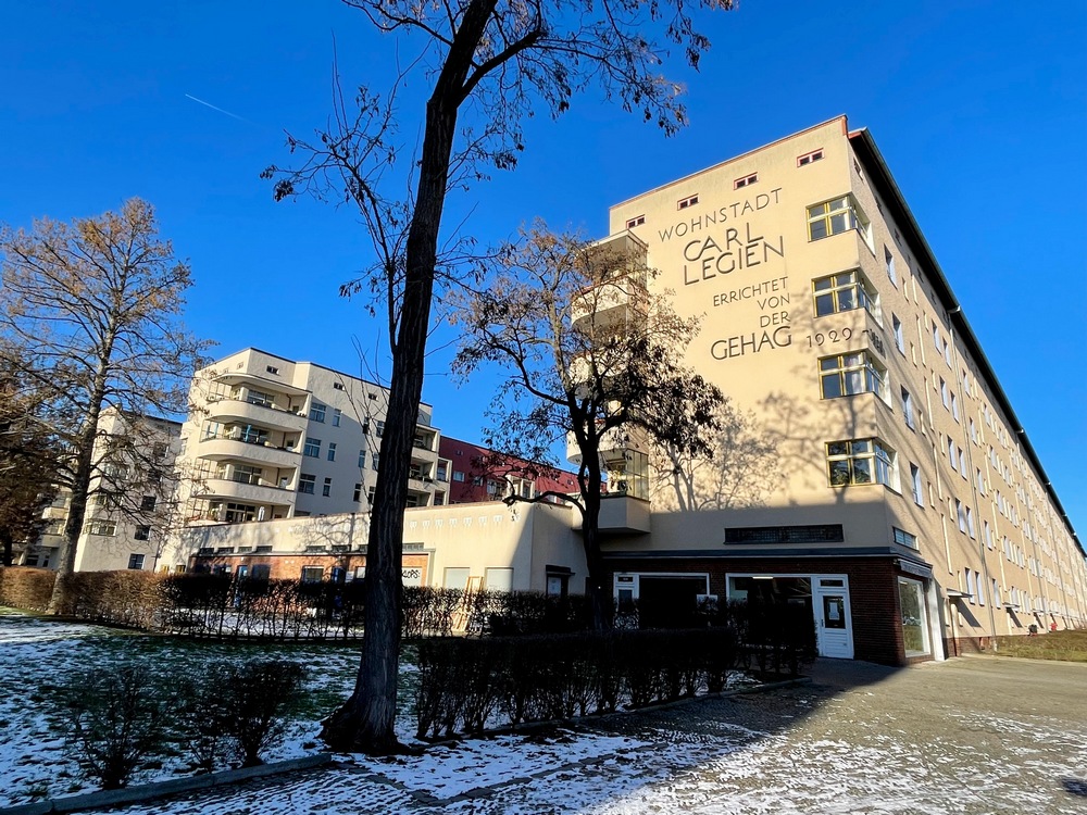 A light-brown row of 6-story apartment buildings with rounded balconies.