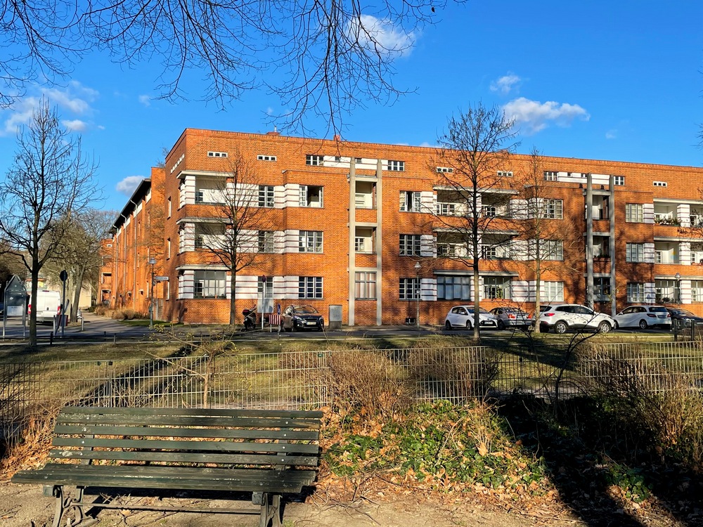 A red-brick apartment building, 4 stories tall, with balconies.