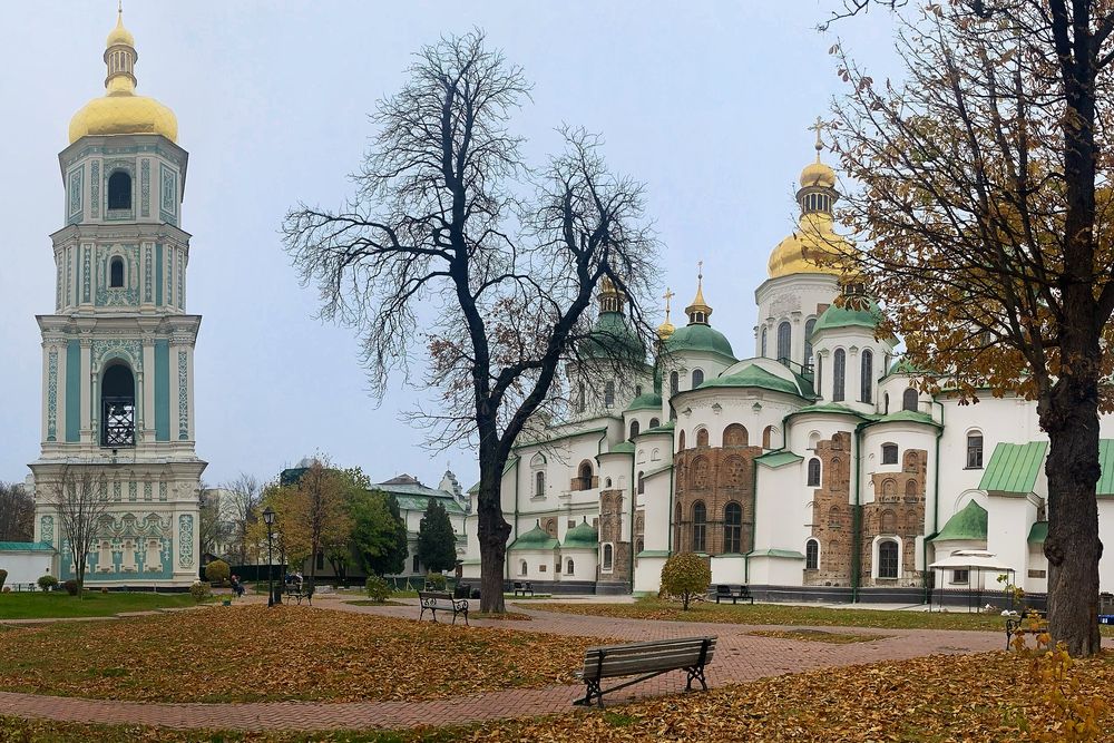 On the left, the bell tower in white and blue with a gold domed roof. On the right, Saint Sophia's Cathedral, white with green domes and one larger gold dome.