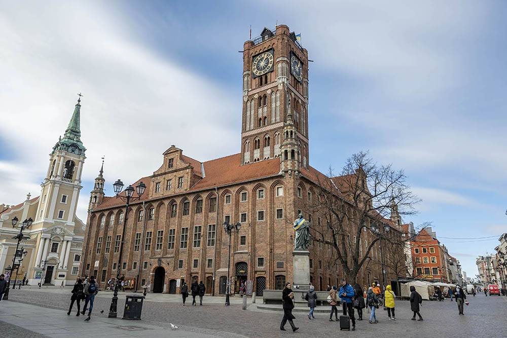 A stately City Hall: brick several stories, with turrets on the corners and a high square tower with a clock.